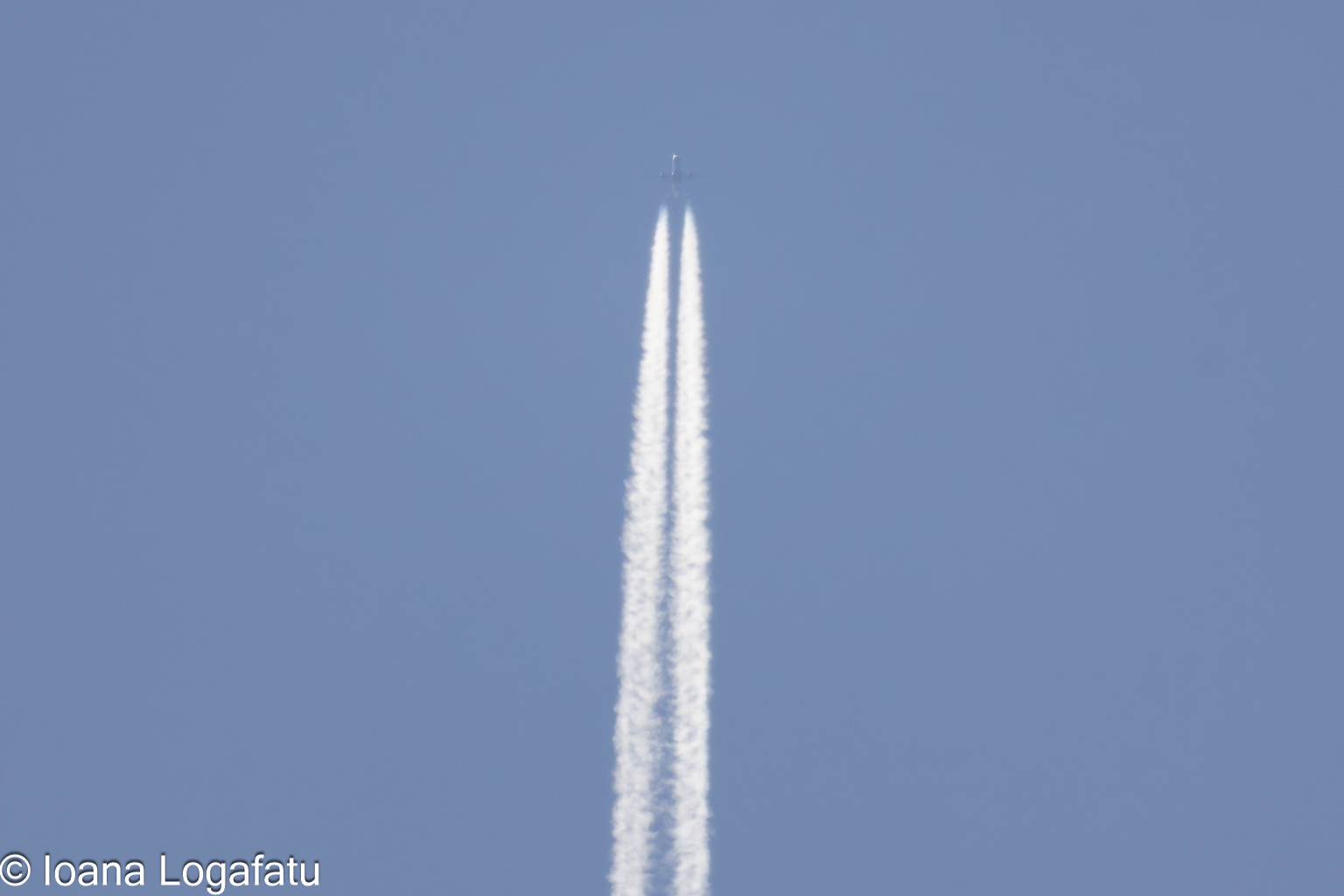 Contrails stretch across the clear blue sky